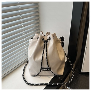 Détail d'un sac seau crème avec fermeture à cordon et bandoulière tissée