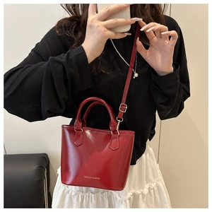 Close-up of shiny red vintage bucket bag with gold lettering shown in mirror