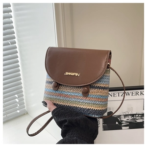 Detail of colorful striped woven bucket bag with brown leather flap and golden logo
