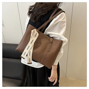 Detailed view of brown leather tote bag with FASHION ribbon and adjustable metal buckle