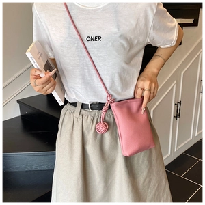 Detail of pink pebbled leather crossbody mini bag with woven ball charm decoration