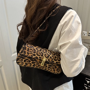 Elegant leopard print baguette bag with gold metal buckle shown on a model's shoulder