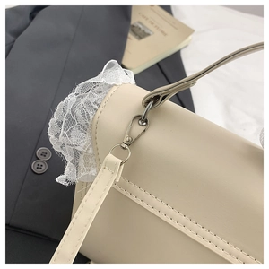 Détail de la texture cuir crème avec dentelle blanche délicate et fermoirs en métal argent