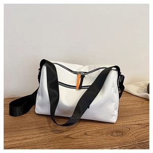 Detail of white nylon crossbody bag with dual black zippers and orange pull tabs