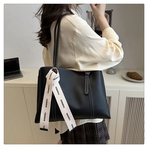 Detail of black tote bag with white contrast stitching and fashion letter ribbon