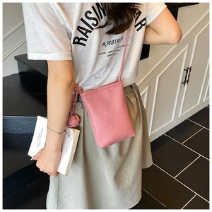 Detail of pink lychee leather phone bag with woven knot charm on white printed t-shirt