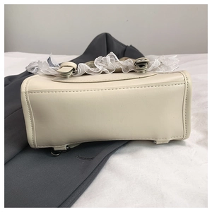 Détails du sac en cuir blanc crème avec bordure en dentelle et pieds de protection