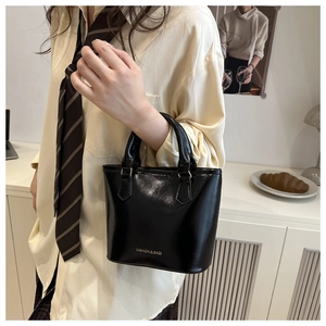 Detailed close-up of shiny black bucket bag with gold Fashion & Bags lettering