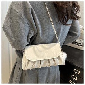 Detail of cream pleated crossbody bag with chain strap and soft plush pompom accessory