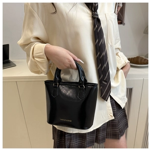 Detail of black patent leather handbag with FASHION & BAGS text and glossy finish