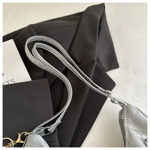 Detail of silver metallic textured tote bag with thin straps and golden hardware hooks