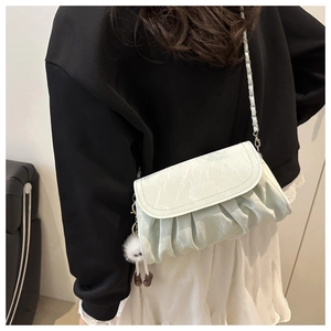 Detail of light green pleated crossbody bag with chain strap and cute plush charm