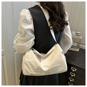 Close-up of white nylon crossbody bag with purple drawstring detail and wide strap