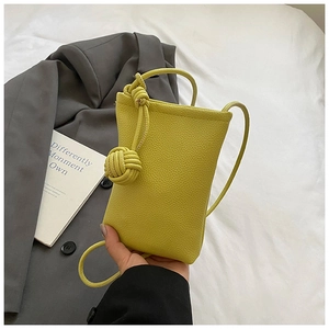 Detail of lime yellow mini crossbody bag with litchi grain and woven knot decor