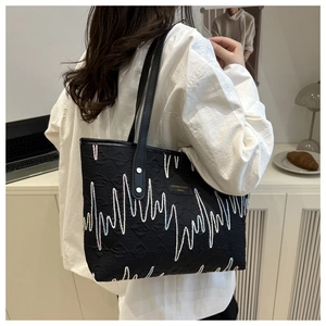 Dettaglio borsa tote nera trapuntata con ricami a onde colorate e placchetta in metallo