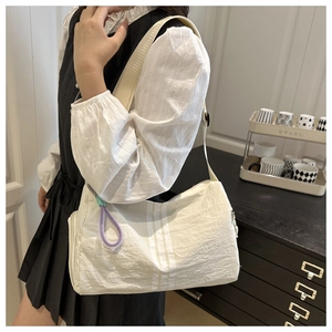 Close-up of a white striped nylon crossbody bag with colorful woven rope accents