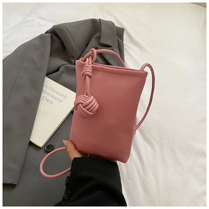 Detailed macro view of pink PU leather texture and knotted handle on a mini crossbody bag