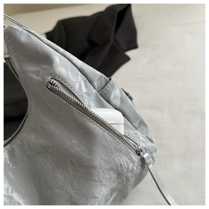 Close-up of silver pleated tote bag with front zipper pocket and metallic texture