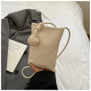 Detail of cream crossbody phone bag with lychee texture and knot shoulder strap