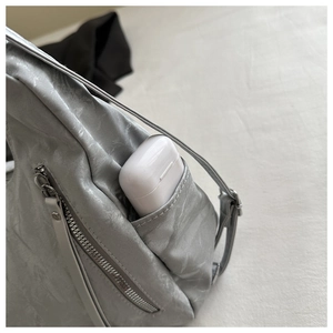 Detail of silver metallic tote with side pocket storing wireless earbud case