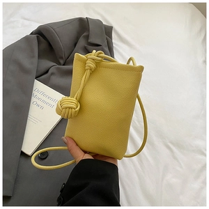 Detail of yellow lychee pattern mini bucket bag with a stylish woven knot strap