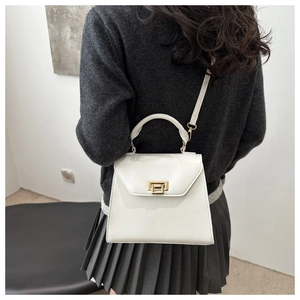 Minimalist white trapezoid handbag with gold lock shown in a crossbody styling view