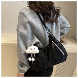 Detail of black pleated shoulder bag with silver zipper and white cloud charm
