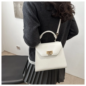 Detailed side view of white Kelly bag with golden twist lock and adjustable strap