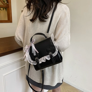 Sac à bandoulière en PU noir avec dentelle blanche et nœud dans un décor intérieur