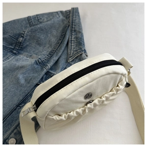 Detailed top view of a cream nylon tote bag with pleated design and black zipper closure