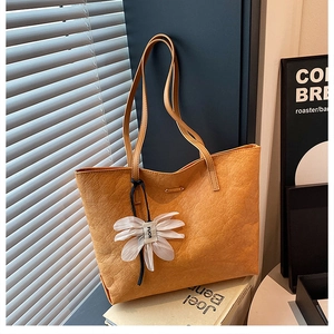 Detail der gelben Shopper-Tasche mit Knitteroptik und weißem Blumenanhänger-Dekor