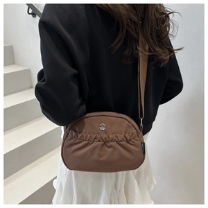 Detail of a brown nylon crossbody bag with pleated design and metallic M logo