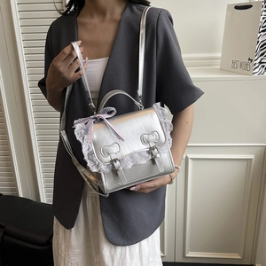 Sac à main en cuir argenté avec bordure en dentelle et nœuds porté par un mannequin
