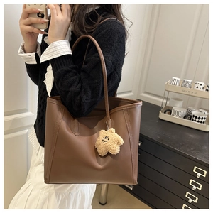 Detail of dark brown tote bag with vertical stitching and cute star plush pendant accessory