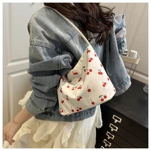 Lifestyle shot of white canvas bucket bag with cherry print and long shoulder strap