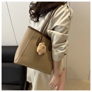 Detail of khaki and brown tote bag with fuzzy bear charm for daily commuting style