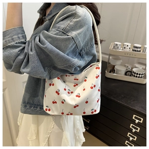 Detailed shot of white fabric bucket bag featuring vibrant red cherry patterns