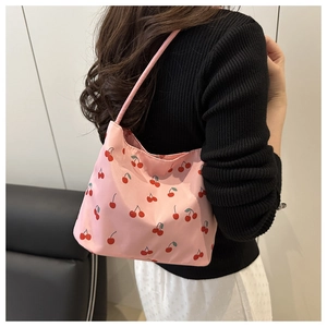 Detailed back view of a pink canvas shoulder bag with red cherry prints on a model