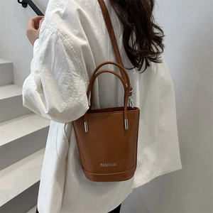 Retro brown leather bucket bag with top handles and adjustable strap shown on model