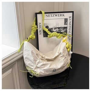 Détail du sac plissé crème avec une bandoulière froncée vert néon éclatante
