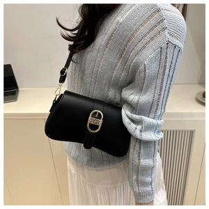 Borsa sottobraccio chic in pelle nera opaca con fibbia dorata indossata con outfit