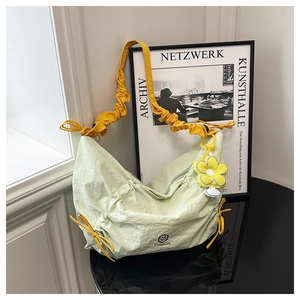 Détail du sac bandoulière plissé vert clair avec sangle jaune et pendentif tournesol