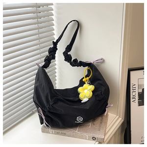 Détail du sac croissant en nylon noir avec bandoulière froncée et pendentif tournesol