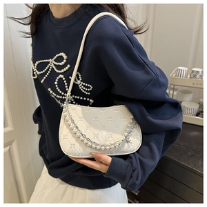 Detail of white quilted underarm bag with elegant pearl chain and star charm decoration