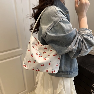White cherry print bucket bag with crescent shape worn by a model in casual style