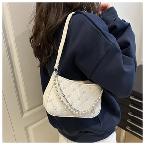 Detail of white half-moon bag featuring quilted embroidery, pearl and metal chains