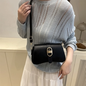 Borsa sottobraccio nera minimalista con fibbia a D dorata indossata da modella