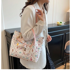 Detail of cartoon print tote bag with pearl chain and plush bunny charm on white suit