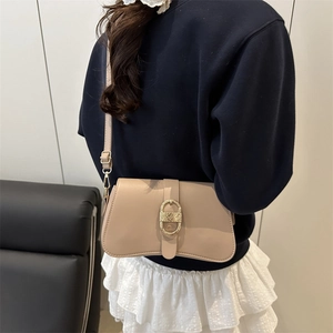Elegante borsa sottobraccio beige con fibbia dorata mostrata su una modella in interno