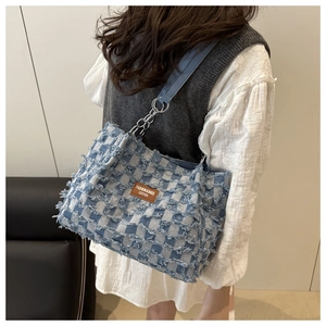 Detail of denim checkerboard tote bag with floral frayed edges and leather brand tag